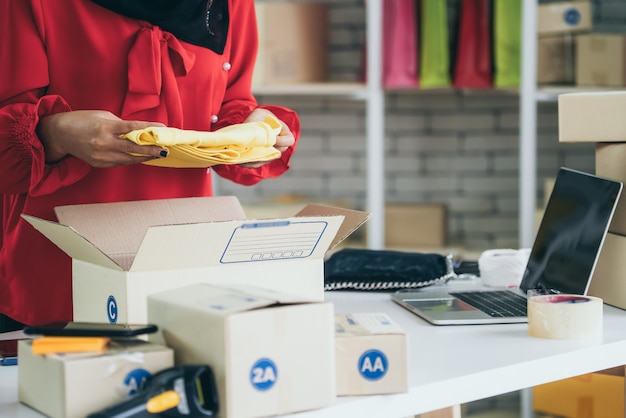 Il venditore online lavora a casa e confeziona la scatola di consegna al cliente.