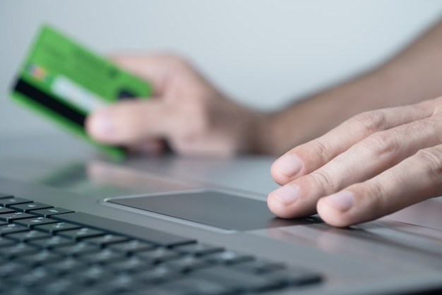 Online shopper uses a laptop. He pays with a credit card.