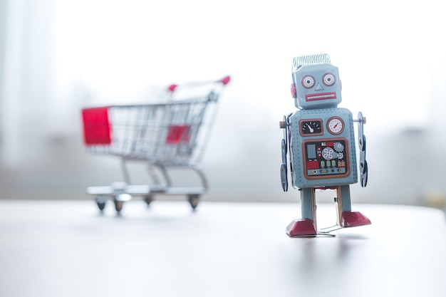 Online shopping algorithm concept Toy robot on the desk shopping cart in the blurry background