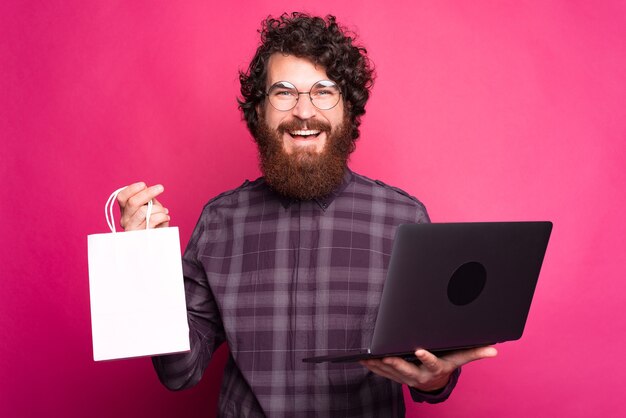 Online shopping, cheerful bearded hipster man holding