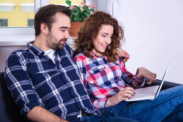 Концепция онлайн-покупок - веселая пара ищет что-то в Интернете на ноутбуке дома