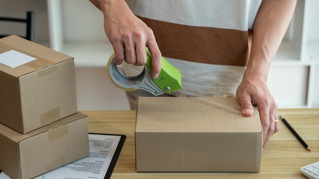 Online shopping concept the shop seller sealing the parcel of his goods on the desk