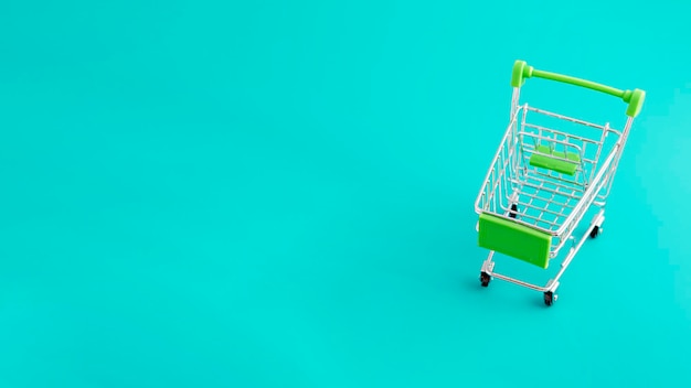 Online shopping concept shopping cart on green background with copy space