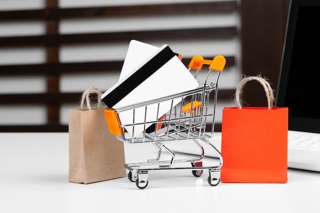 Online shopping concept. Shopping cart, laptop on the desk