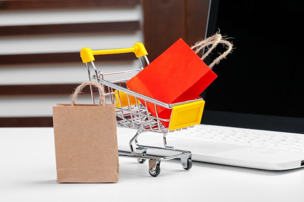 Online shopping concept. Shopping cart, laptop on the desk