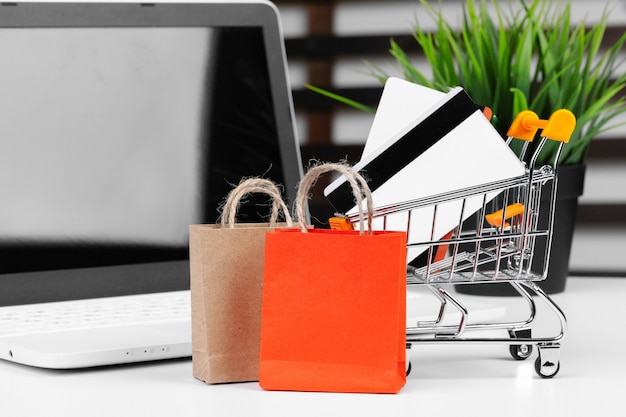 オンラインショッピングの概念。ショッピングカート、机の上のノートパソコン