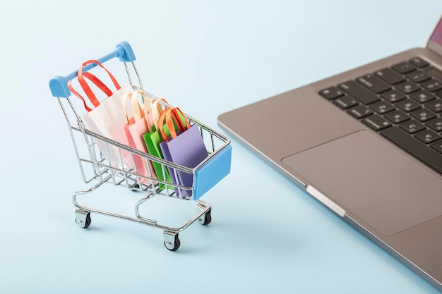 Online shopping concept shopping cart small boxes laptop on the desk