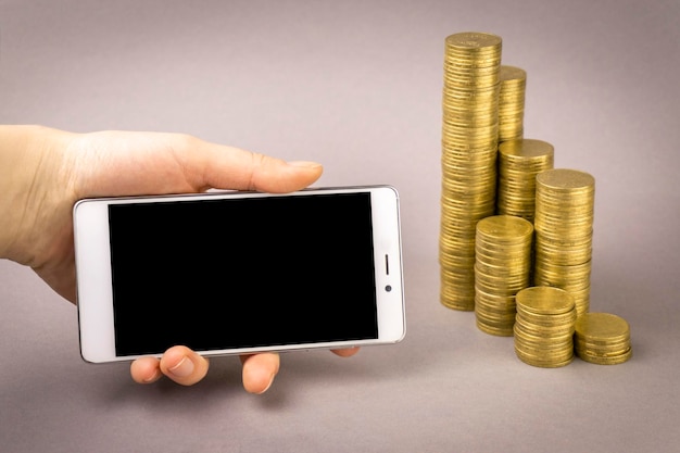 Online shopping concept white smartphone and coins on a gray background