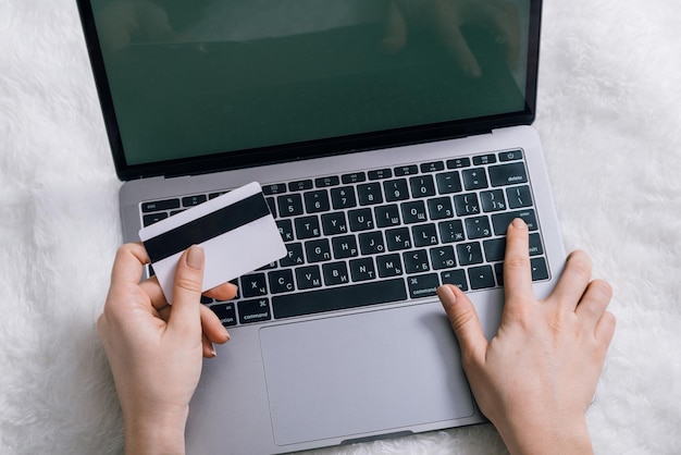 Online shopping concept woman hands hold bank card laptop on background