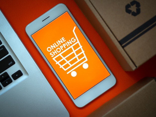 온라인 쇼핑 개념. 단어 "온라인 쇼핑"및 스마트 폰 화면에 주황색 배경에 쇼핑 카트 아이콘.