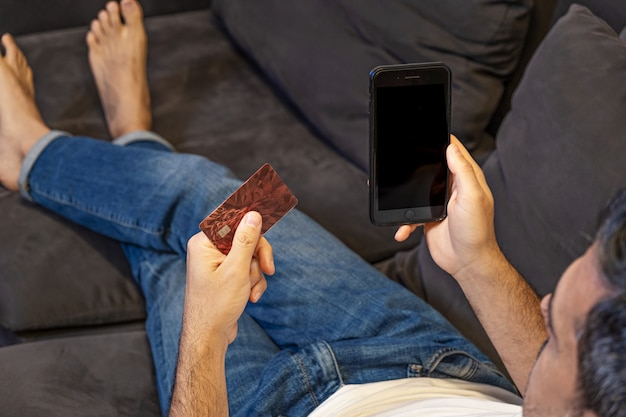 Online shopping mock up. man paying order online with the phone and credit card from home