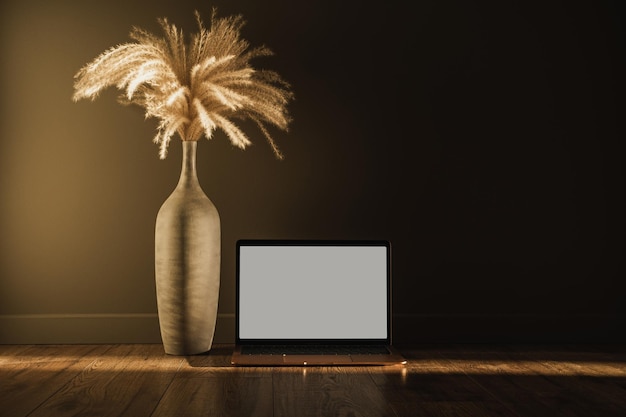 Online shopping online store template Laptop computer with blank copy space screen Aesthetic minimal pampas grass floral bouquet against shaded wall Shadows on the wall Silhouette in sunlight