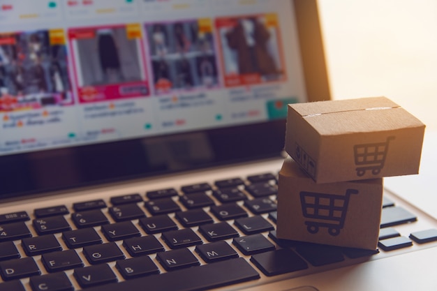 Online shopping : Paper cartons or parcel with a shopping cart logo on a laptop keyboard. Shopping service on The online web and offers home delivery.