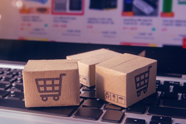 Online shopping - Paper cartons or parcel with a shopping cart logo on a laptop keyboard. Shopping service on The online web and offers home delivery.
