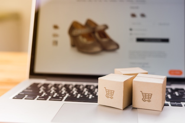 Photo online shopping - paper cartons or parcel with a shopping cart logo on a laptop keyboard which web store shop on screen, shopping service on the online web and offers home delivery.