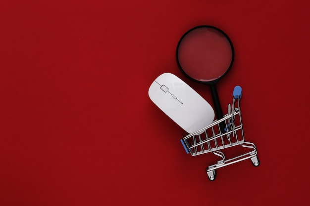 Онлайн покупки. Компьютерная мышь и мини-тележка для покупок с часами на красном фоне. Вид сверху. Плоская планировка