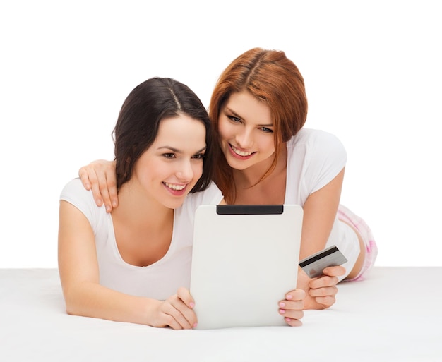 オンラインショッピングとテクノロジーのコンセプト-タブレットPCコンピューターとクレジットカードを持った2人の笑顔の10代の少女