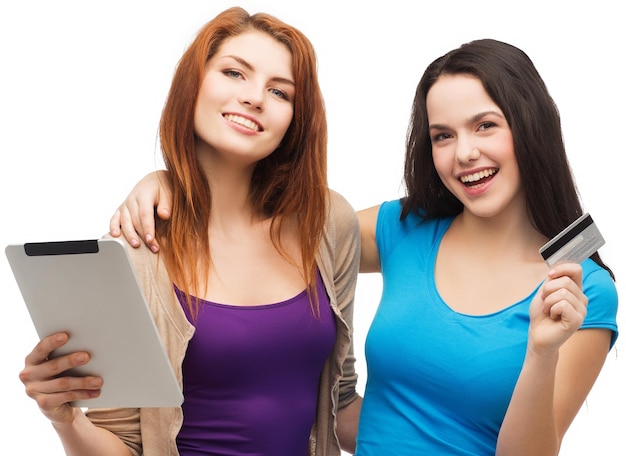 Foto shopping online e concetto di tecnologia - due adolescenti sorridenti con computer tablet pc e carta di credito