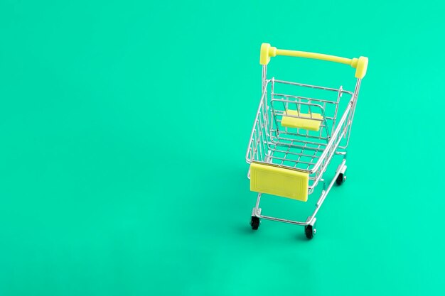 Online shopping via the Internet concept supermarket trolley on a green background with copy space