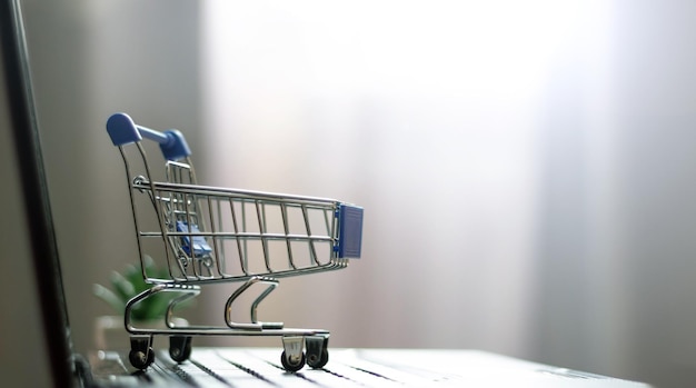 Online shopping with home delivery. Shopping basket on laptop keyboard.