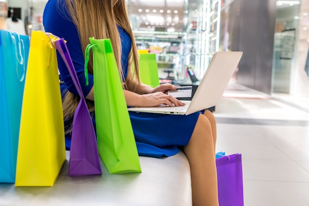 Foto shopping online, donna in un centro commerciale con laptop e carta