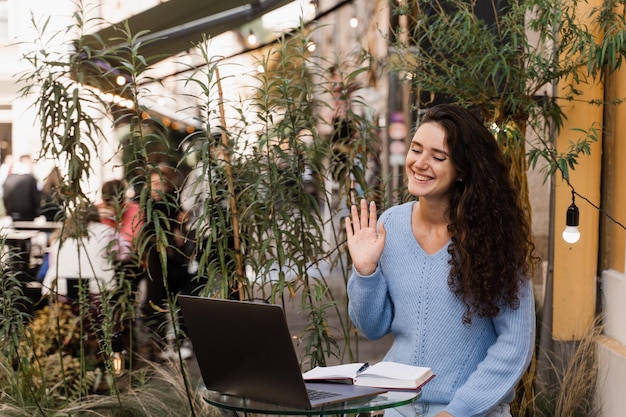 Online sollicitatiegesprek van kandidaat-meisje met HR-manager in IT-bedrijf buiten Zelfverzekerd meisje met laptop communiceert en praat over zichzelf via videocommunicatie in café buiten