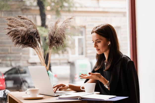 Online sollicitatiegesprek van meisjeskandidaat met HR-manager in IT-bedrijf Zelfverzekerd meisje met laptop communiceert en praat over zichzelf via videocommunicatie in café Solliciteren