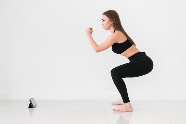 Online sporttraining en vrouw die squats doen