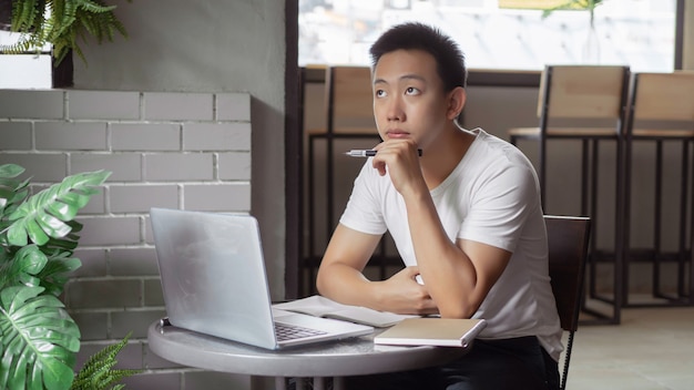 Online studeren concept de jonge man in eenvoudig wit T-shirt is attent en serieus voor het scherm tijdens de online les.