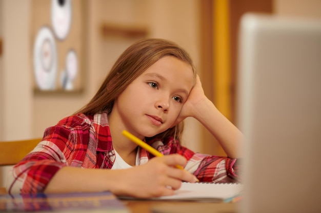 Online studeren. Een schattig langharig meisje met een online tutorial