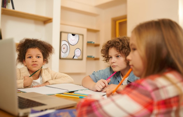 オンライン学習。一緒にリモートで勉強し、何かを書き留める子供たちのグループ