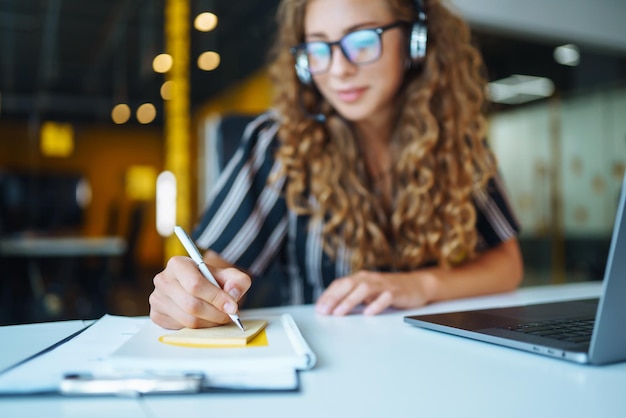 Foto online vergaderen jonge vrouw die een koptelefoon draagt met een laptop die naar een webinar kijkt of videochat doet