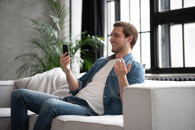 Online videogesprek Positieve man zwaait met de hand naar de webcam en heeft prettig gepraat met vrienden of familie