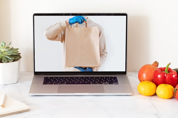 Online voedselbezorgingsconcept met witte laptop met leeg scherm. Boodschappen bezorgservice. Thuiskantoor.