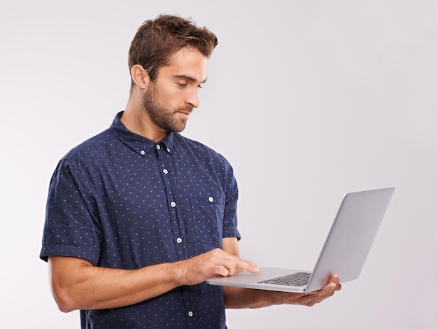 Online vrijheid Een studio-opname van een knappe man die een laptop gebruikt