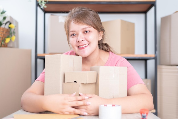 Online werk verkopen vanuit huis Vrouwelijke bedrijfseigenaar die thuis werkt met verpakkingsdoos