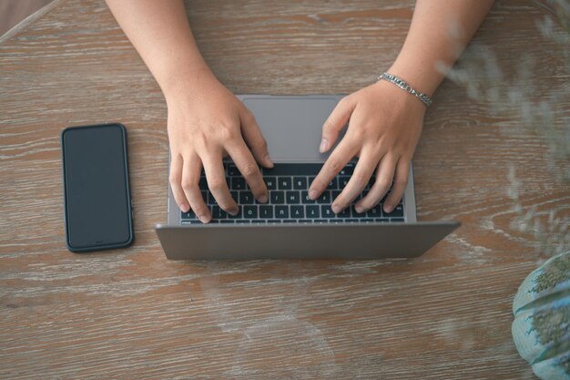 Online werken vanuit huis draagbaar kantoorconcept Bovenaanzicht hand van jonge man aan het werk op laptop