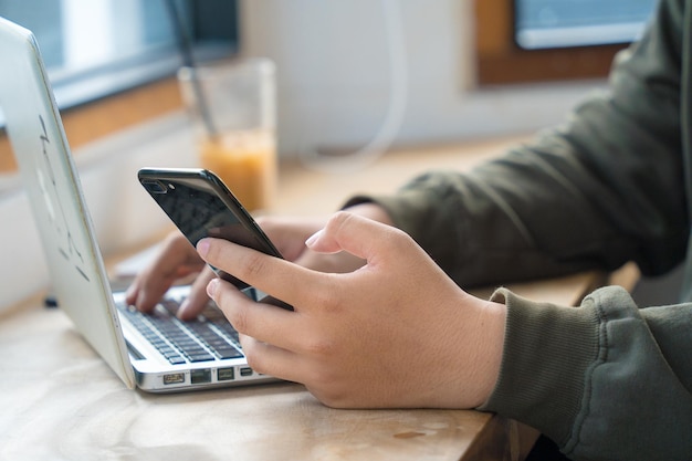 Online werken vanuit huis draagbare kantoor concept zijaanzicht hand van jonge man aan het werk op mobiele telefoon