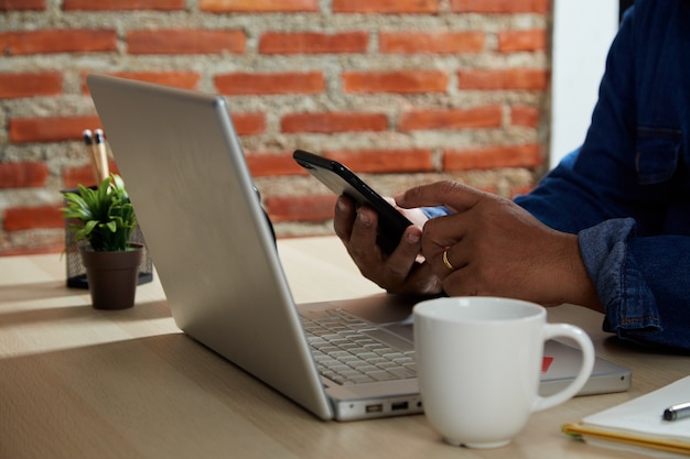 Online winkelconcept, close-up jonge man met behulp van mobiele smartphone en creditcard die online betaalt met laptopcomputer op tafel