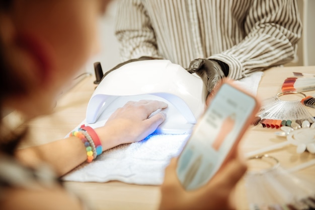 Foto online winkelen. blondharige stijlvolle tiener die online winkelt terwijl ze manicure heeft