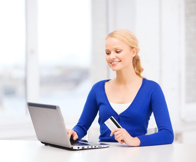 online winkelen en technologieconcept - glimlachende jonge vrouw met laptopcomputer en creditcard