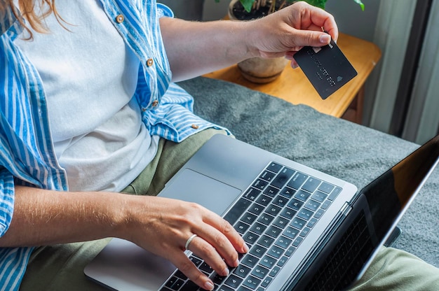 online winkelen met een creditcard meisje zit op het bed achter de computer in haar handen