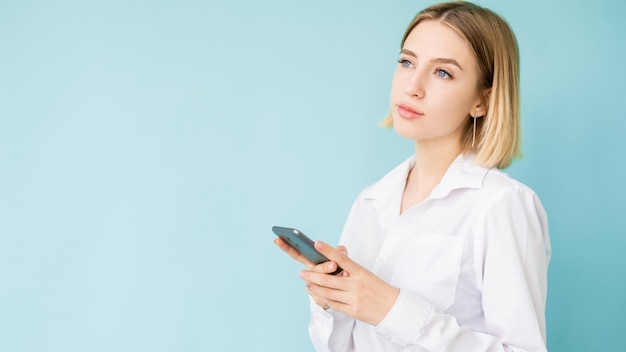 Online winkelen Office vrouw Mobiele technologie Reclame achtergrond Doordachte dame denken over aankoop smartphone in handen geïsoleerde blauwe kopie ruimte
