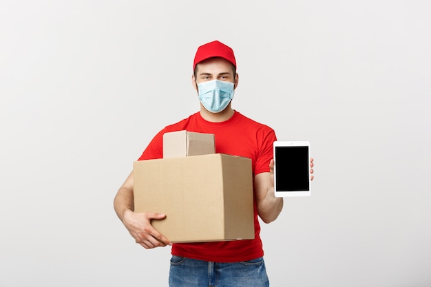 Online winkelend, levering, technologie en levensstijlconcept - glimlachende leveringsmens die tablet voorstellen en dozen in zijn hand houden. geïsoleerd over witte studiomuur.