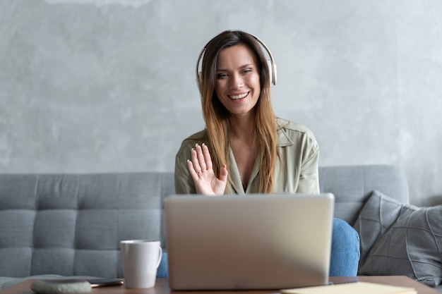 Online work at home. A woman using laptop she speaks with a partner through the video call chat application at home.