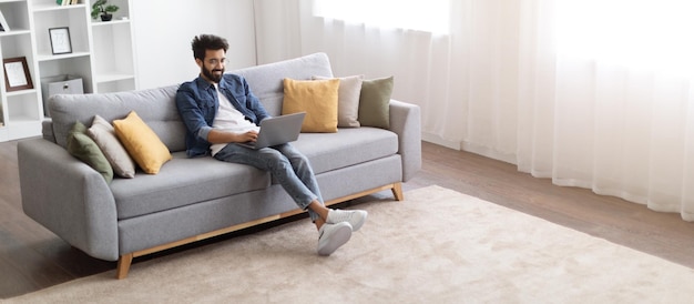 Online work millennial indian freelancer guy using laptop computer at home