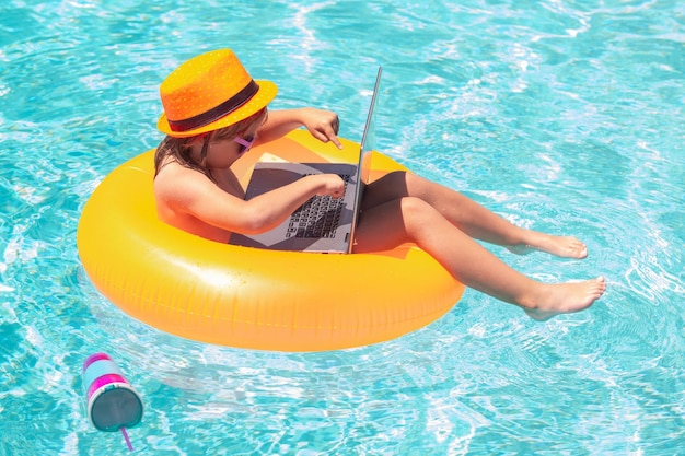 Online working and relax in pool child with laptop in swimming pool in summer day