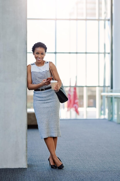 The only thing that attracts success is positivity Full length portrait of an attractive young businesswoman smiling while using a smartphone in a modern office