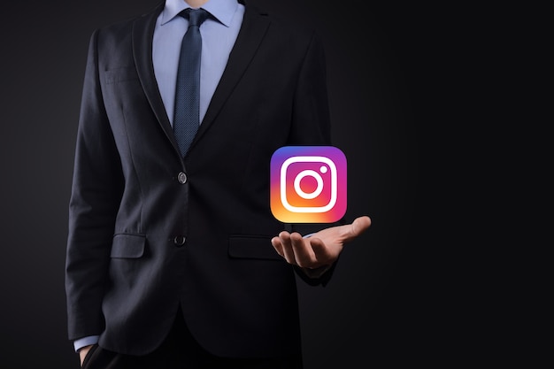 写真 ウクライナ、オノク-2021年7月14日：ビジネスマンは、instagramアイコンを手に持ってクリックします。ソーシャルネットワーク。グローバルネットワークとデータ顧客接続。国際ネットワーク。