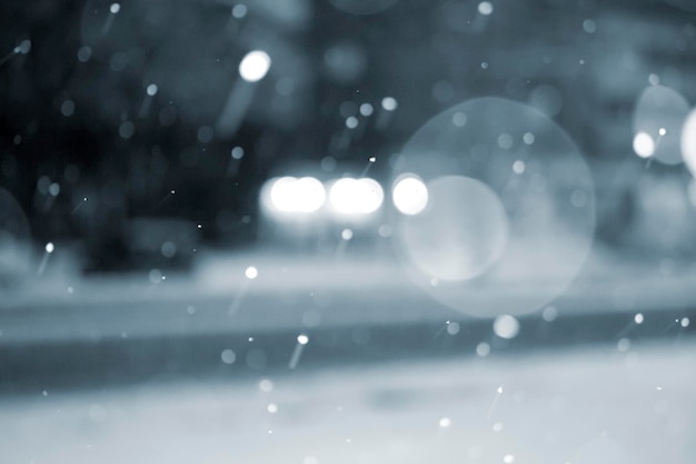 Onscherpe achtergrond auto's rijden op de weg in de stad tijdens sneeuwval op winternacht wazig bokeh vlekken s